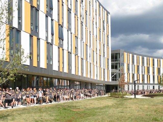 Freshmen students tour the outside of Holly Pointe Commons residence hall.