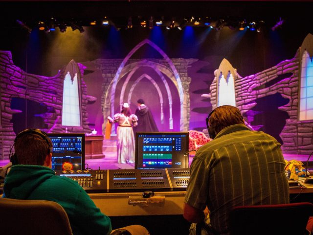 student performers practice Dracula on stage as tech students look on