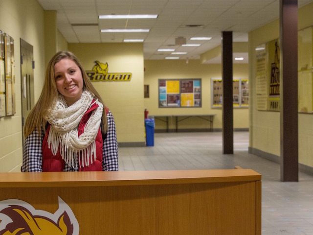 student stands behind a desk