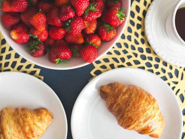 bowl of strawberries and croissants on a kitchen table