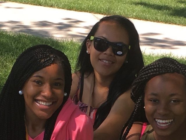 3 girls smile sitting on the grass