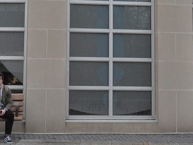 Greg sits on a bench outside of the Campbell Library