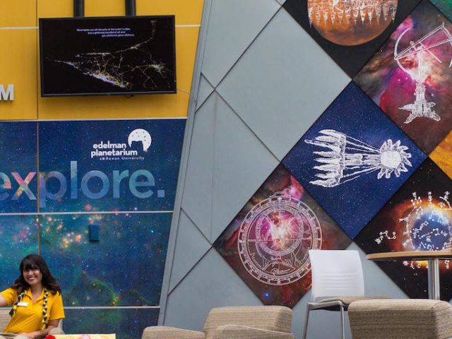 Kathy sitting in Science Hall lobby in front of the Planetarium.