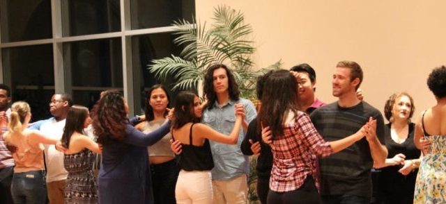 Ballroom dance club members stand facing their partners in the ballroom