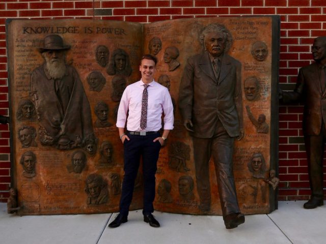 Evan standing outside of James Hall at statue