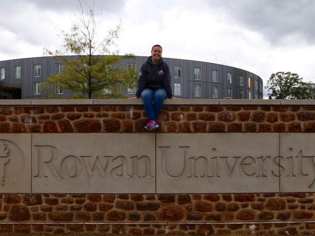 Jereca sitting on Rowan University brick sign outside of Holly Pointe