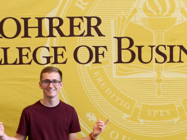 Kyle in front of Rohrer College of Business sign