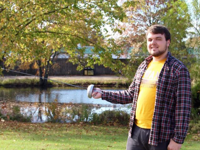 Michael with his fencing blade outside near a pond