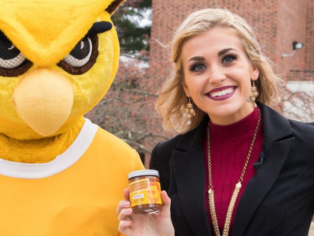 Rowan student stands next to the prof holding hot sauce