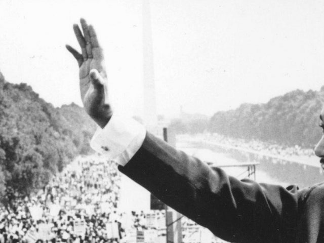 iconic photo of Dr. Martin Luther King waving at crowd after a speech