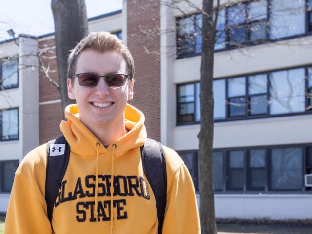 Scott Timko is a resident assistant in Mullica Hall, wearing a yellow sweatshirt that says Glassboro State