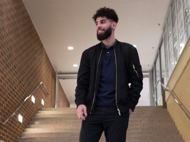 Nabil walks down the stairs in James Hall at Rowan University