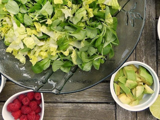 a table with plates of fresh veggies and salad on it