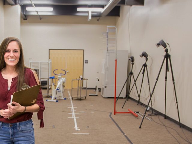 female student in hallway surrounded by pt equipment