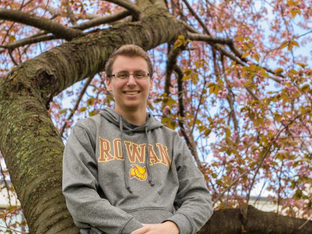 Scott the RA in a pink tree outside Mullica at Rowan