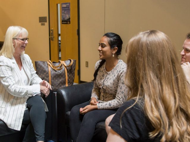 Rowan University Professor Kathy Balin sitting in Savitz hall chatting with 3 students