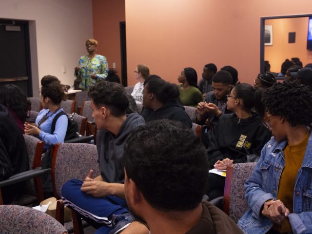 a room full of students looks on as a faculty speaker presents her thoughts on professional behavior at job interviews.