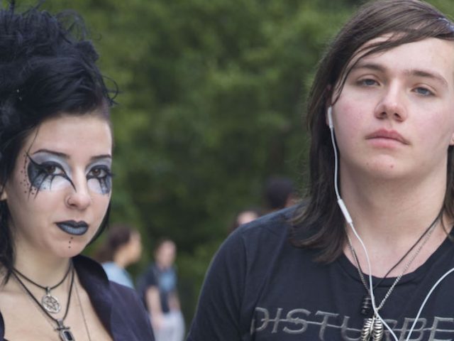 Concetta Davis (left), dressed in goth style with all black clothing and eye makeup stands next to her friend wearing a Disturbed shirt.