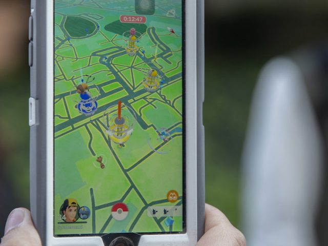 a close-up of a student holding a phone with the pokemon go app open.