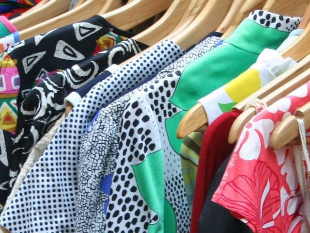 close up of shirts with variety of patterns and colors hanging on hangers in a closet