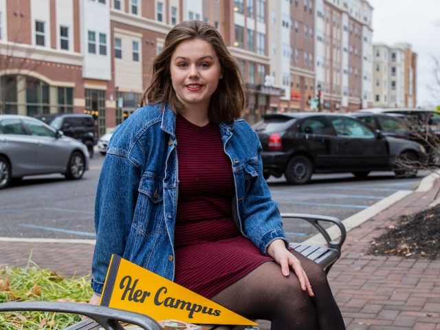 Rachel outside Barnes and Nobles sitting on bench with her books and Her Campus pennant