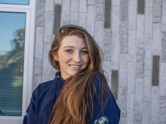 Kallie stands facing camera head turned over shoulder, with long hair down to her waist