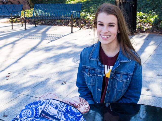 Skylar sits outside the student center at a solar panel powered bench