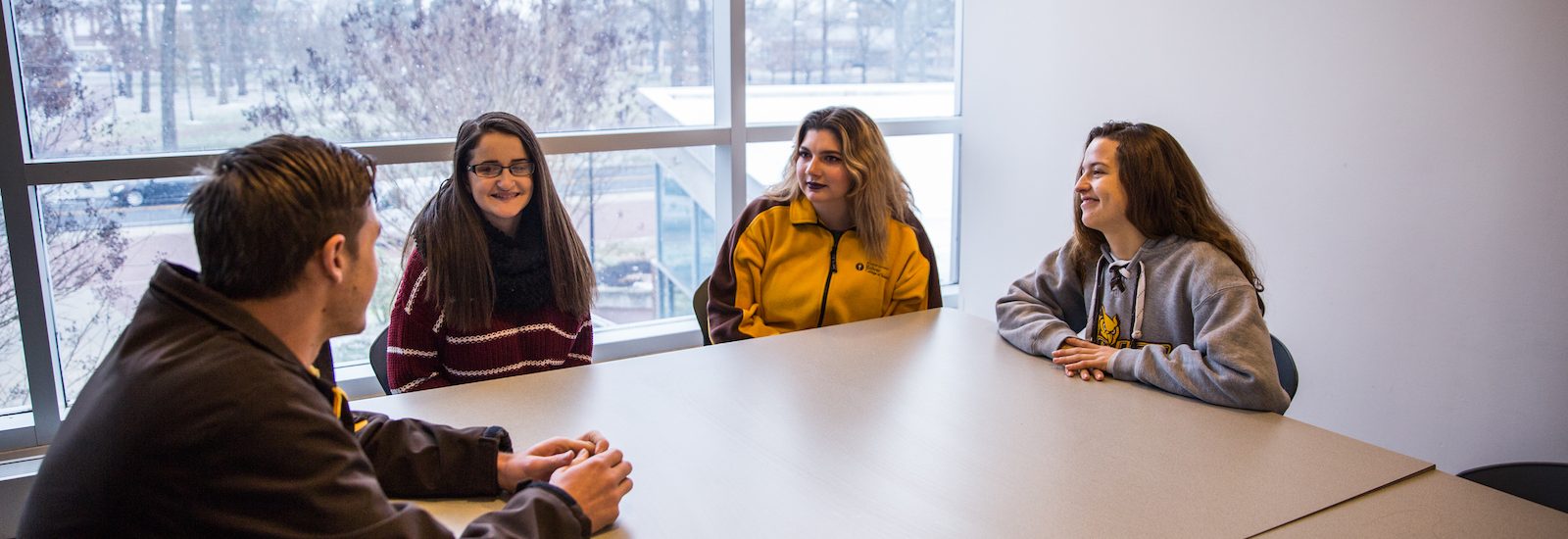 Liz and her friends sitting upstairs in Savitz hall by a snowy window