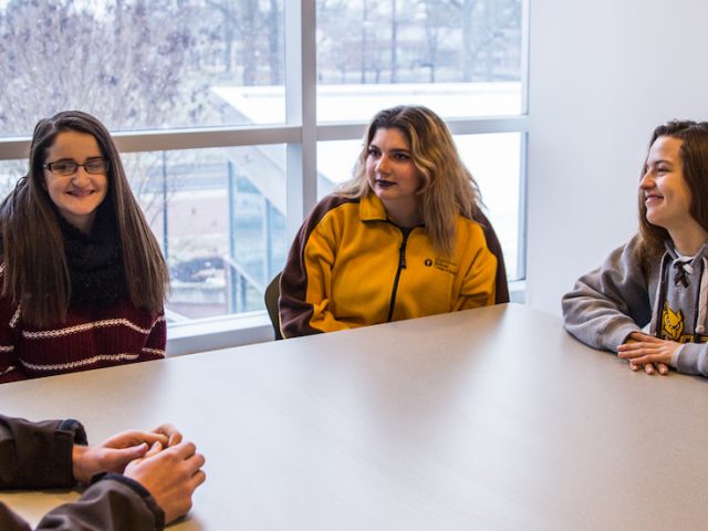 Liz and her friends sitting upstairs in Savitz hall by a snowy window