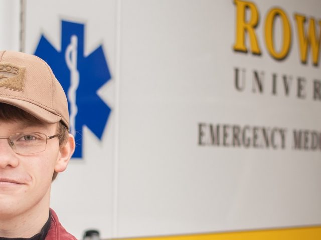 Young man standing in front of a white and yellow Rowan EMS vehicle