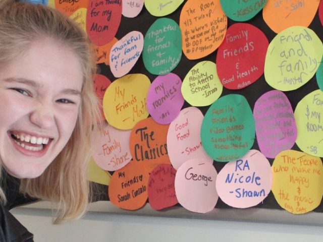 Nicole Grant laughs as she stands in front of a colorful bulletin board she made as a resident assistant.