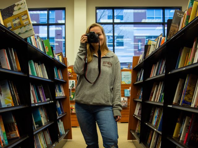 student inside Barnes and Nobles on campus in book aisle taking a photo