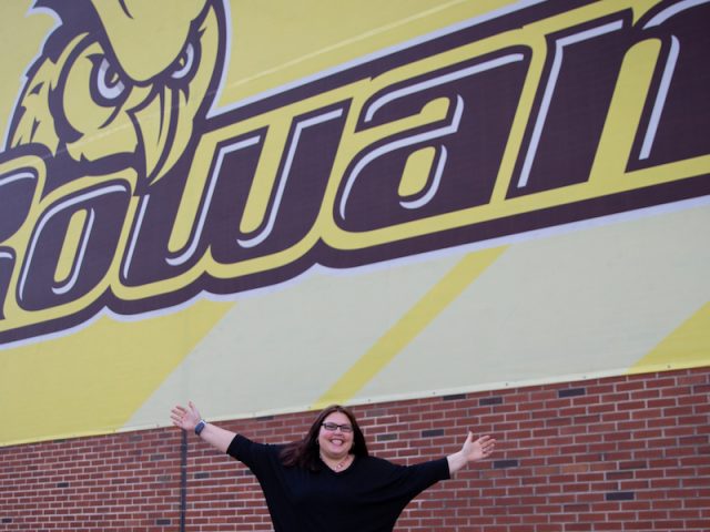 Kara outside of Rowan Sign holding her hands up in the air