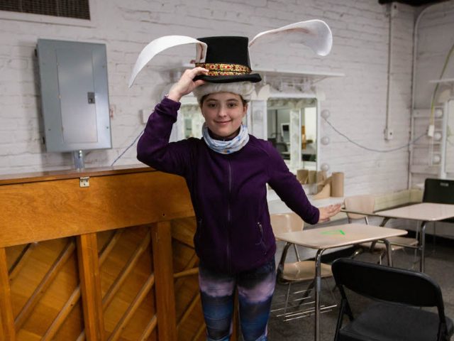 Student Isabel wearing a prop hat inside the rehearsal room