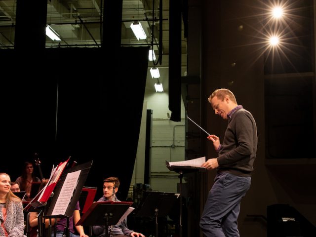 Professor Higgins conducting the ensemble on stage in Pfleeger Hall