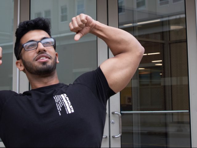 Young male student flexing in front of glass doors