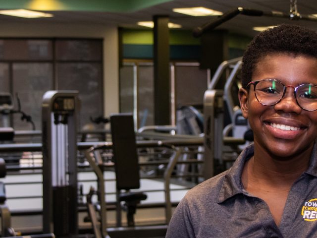 Woman leaning on counter inside with multiple gym machines in the background