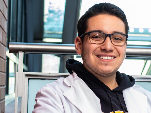 Zachary Padron wearing a lab coat inside Science Hall