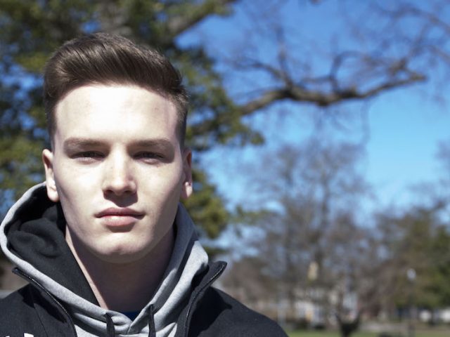 Francis Terry stands in front of a tree for a portrait, wearing a black Rowan zip up