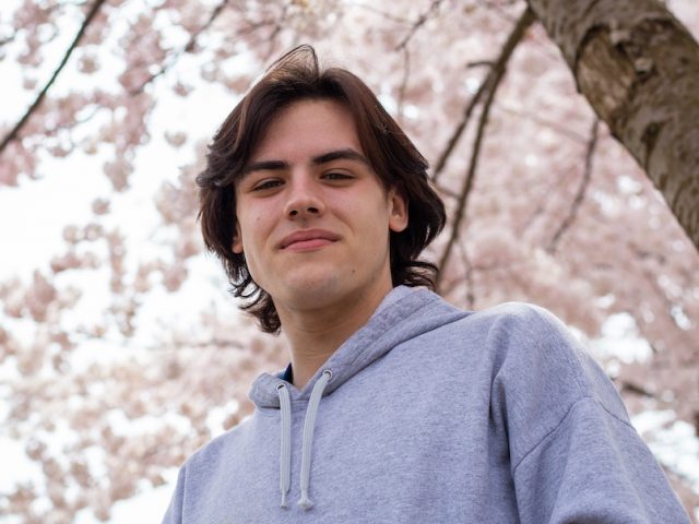 Michael outside with pretty pink flowers behind him at Rowan