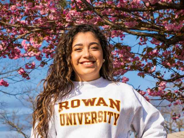 student Allison outside of cherry blossom tree in Rowan hoodie