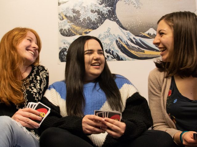 roommates on the bed playing uno cards in friends dorm bedroom in Whitney Center