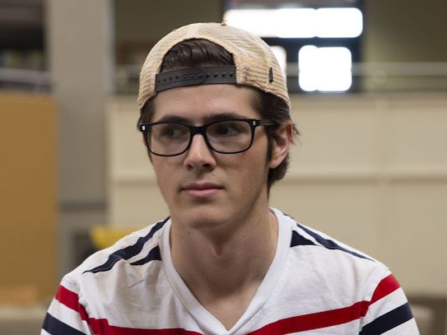 Tom Julian wearing a background hat sitting in the Student Center