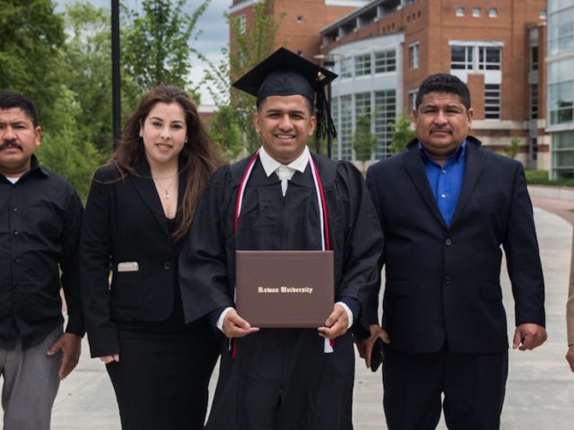 Edwin, in his cap and gown, stands next to his four family members outside Savitz Hall