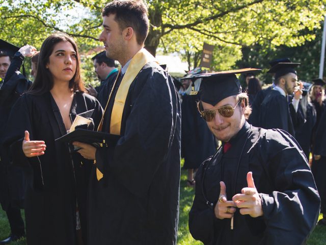 Radio/Tv/Film graduate poses in his black cap and gown.