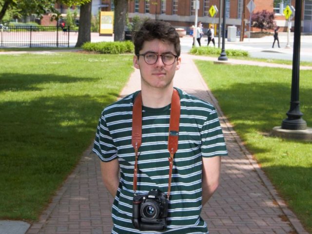 Chad, standing in the gradd of bunce hall with a camera