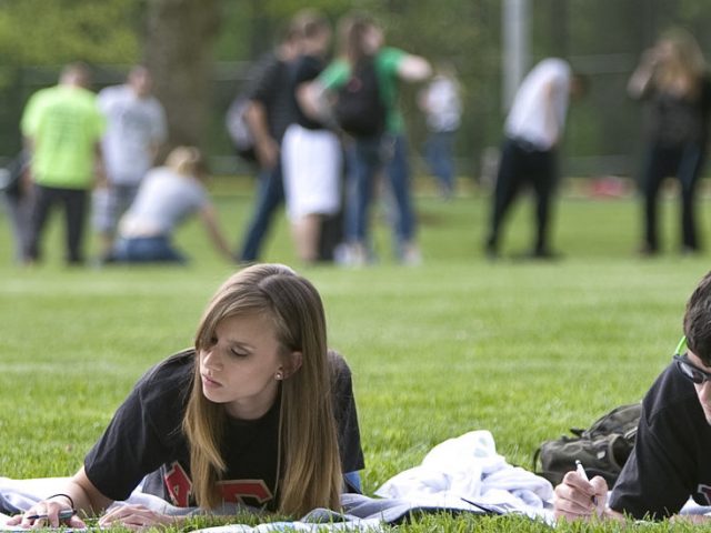 Students studying and playing on a field