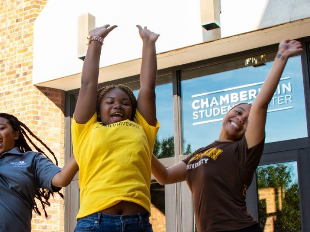 Three Rowan students jumping in front of the Chamberlain Student Center