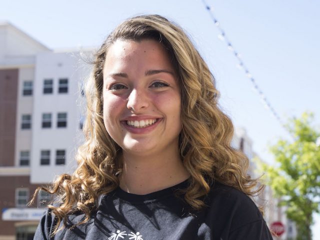 Callie DeMaria stands smiling with Rowan Boulevard buildings behind her at Rowan University