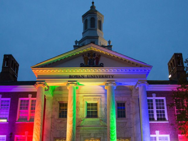 The front of Bunce Hall being lit up at night with rainbow colored lights